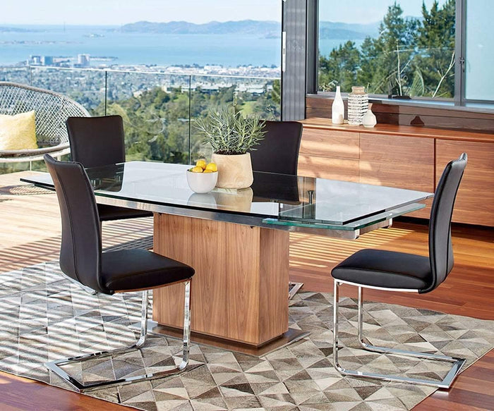 Contemporary dining room featuring a glass table, four Alma Dining Chairs in black, a geometric rug, wooden flooring, and expansive windows showcasing stunning city and bay views. The space is accented by a bowl of fruit and a plant placed on the table.