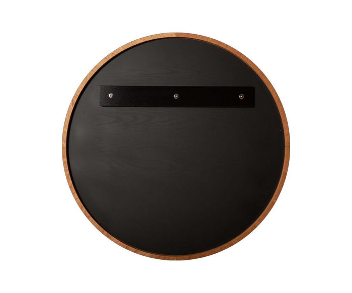 The Baptisia 35″ Round Mirror features a wood frame encircling a black center, highlighted by a horizontal black strip with three screws near the top. Presented against a white background, this mirror effortlessly blends modern artistry into its design.