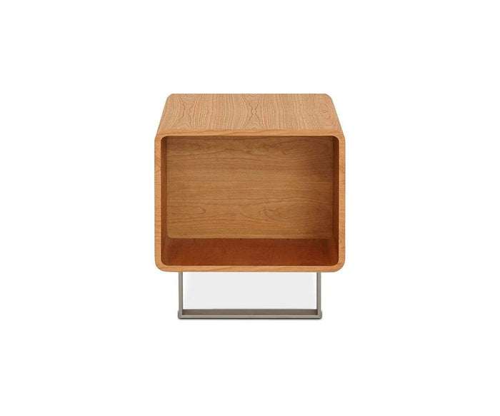 The Baptisia End Table is a small, rectangular wooden table in a CHERRY finish, featuring an open front with no shelves, rounded edges, and a distinctive flat metal base. Its design evokes cubist art sculpture.