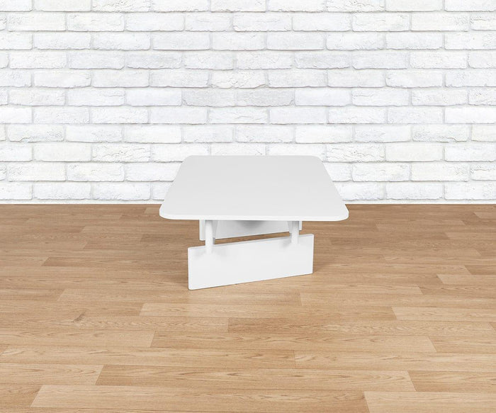 The Batia Coffee Table, featuring a modern marble top and a geometric base, sits on a light wood floor in front of a white brick wall.