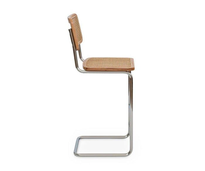 A side view of the Bendt Bar Stool, featuring a modern cantilevered chrome frame, a woven rattan seat and backrest reminiscent of classic cane bar stools, and elegant European beech wood accents along the edges.