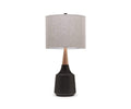 The Bergset Table Lamp showcases a black/multi ceramic base with bold geometric lines, a wooden neck, and a chic grey fabric drum shade, set against a plain white background.