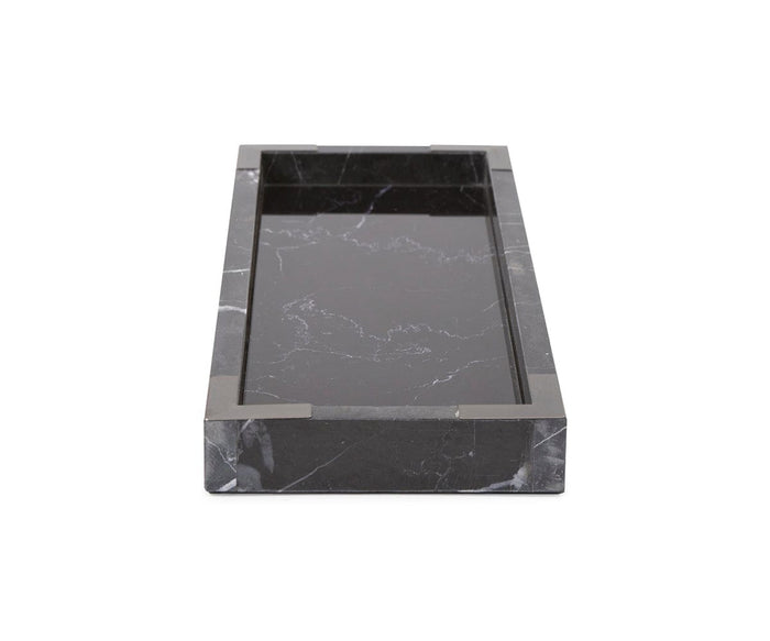 The Black Mirrored Marble Tray, shown in a rectangular form and viewed from a low front angle against a plain white background, showcases its elegant black color with striking white veining. The sophisticated tray’s allure is further accentuated by subtle brushed titanium accents along its edges.