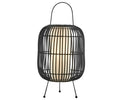 The Clement Table Lamp in black features a modern design with a rounded wire frame, three slim legs, a top handle, and a white cylindrical cordless light inside that is battery-powered and evokes the look of faux rattan.