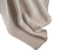 A Cooper Clay–colored knitted blanket draped in soft, wavy folds, with detailed textured stitching throughout the fabric—crafted from cotton yarn for a retro-cozy feel, this is the inviting Cooper Throw.