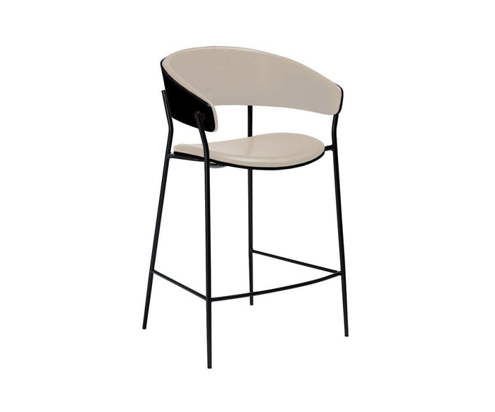 Introducing the Crib Leather Counter Stool—a modern, contemporary bar stool featuring a curved beige leather seat and backrest, supported by slim black metal legs and an integrated footrest. This mid-century modern piece seamlessly combines timeless design with sleek functionality, making it a stylish addition to any space.