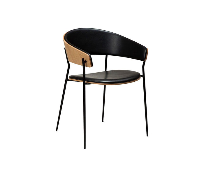 The Crib Leather Dining Chair is a modern piece, featuring a black leather seat and backrest, wooden outer back, and slim black metal legs, set against a white background.