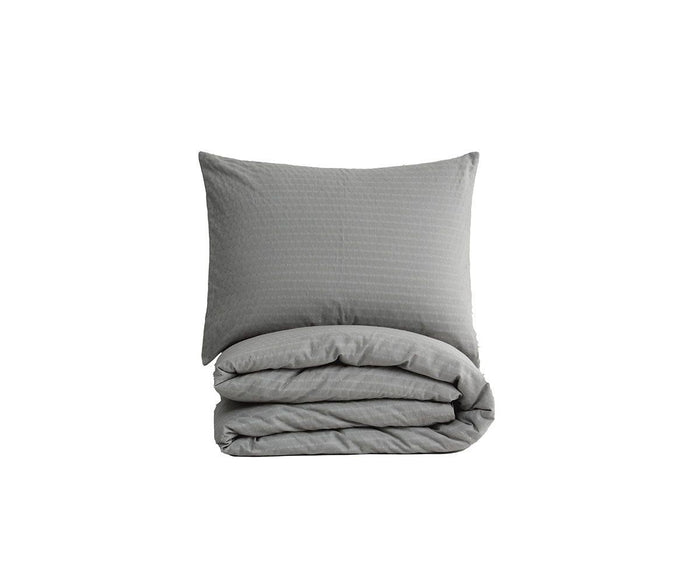 A neatly folded Crinkled Pleats Duvet Cover in grey with a matching sham propped up behind it, both set against a plain white background, highlights the refined texture of this contemporary set.