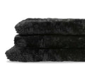 Two plush Curly Double Pelt - Black faux fur throws are stacked neatly against a white background, showcasing the luxurious softness of sheepskin—an essential Scandinavian accent for cozy interiors.