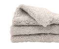 A neatly folded, fluffy Curly Double Pelt in oatmeal—an inviting Scandinavian essential—rests on a white background.