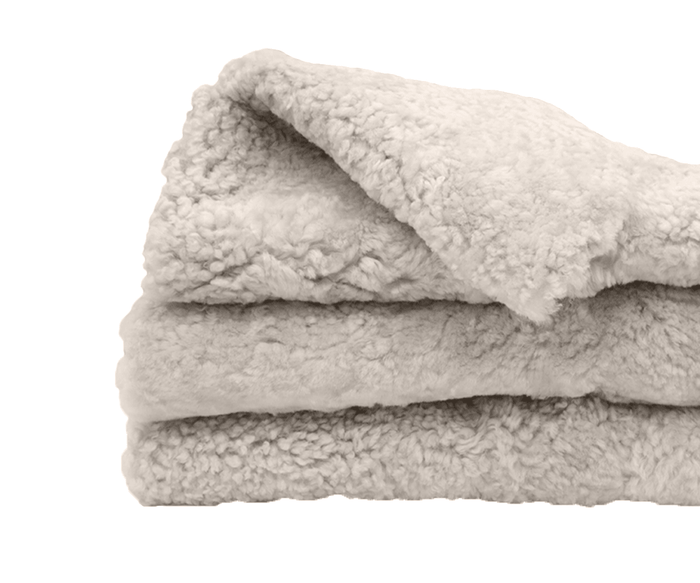 A neatly folded, fluffy Curly Double Pelt in oatmeal—an inviting Scandinavian essential—rests on a white background.