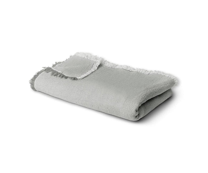 A neatly folded Daisy Gray Daisy Bedcover, made from organic cotton and featuring fringed edges, lies on a white background.