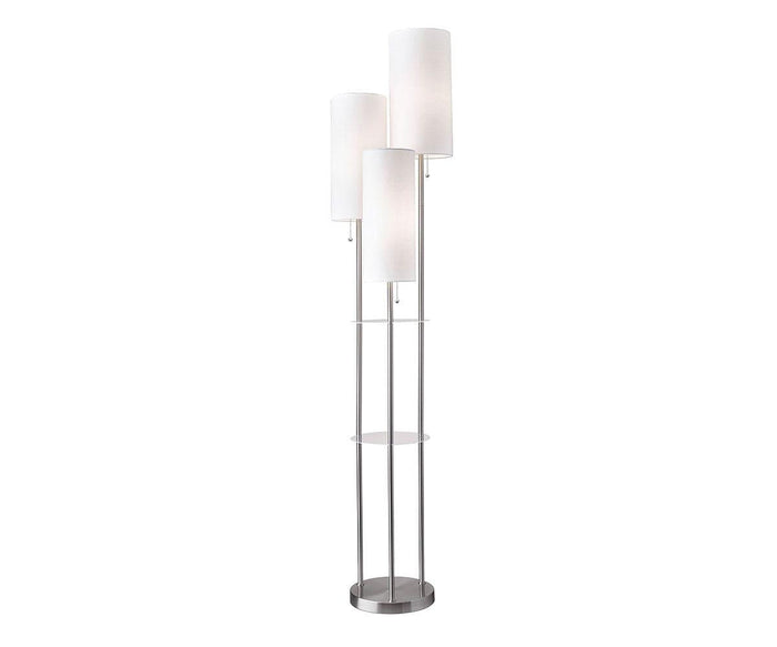 The Daphne Shelf Floor Lamp in brushed steel features three tall, cylindrical white lampshades arranged at different heights on sleek metal rods. A small circular glass shelf at the center provides both style and function to this contemporary floor lamp.