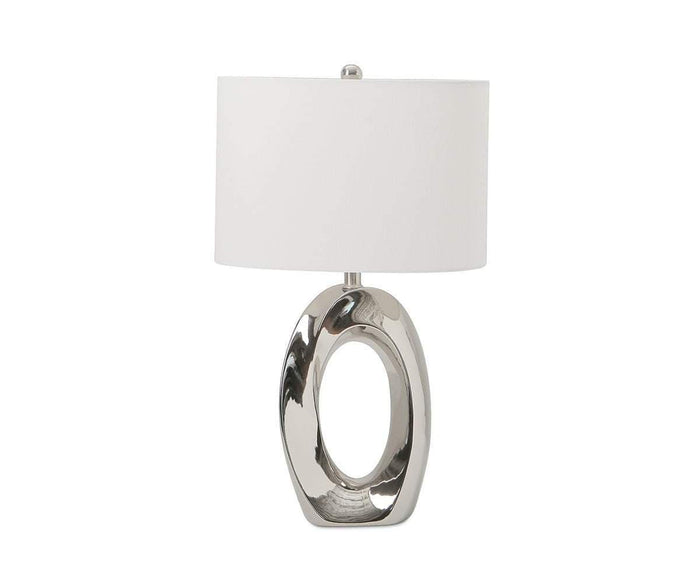 The Darlene Table Lamp showcases a sleek, modern design with its shiny silver, oval-shaped base featuring a hollow center, complemented by a simple white drum lampshade. Reminiscent of a contemporary art sculpture, this lamp adds an artistic touch to any interior.