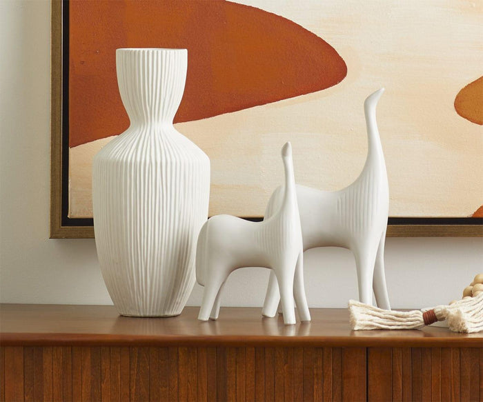 A white textured vase and two abstract white animal figurines are arranged on a wooden surface, set in front of the Desert Oil Painting, which features hand-painted brown and beige shapes reminiscent of desert landscape art.
