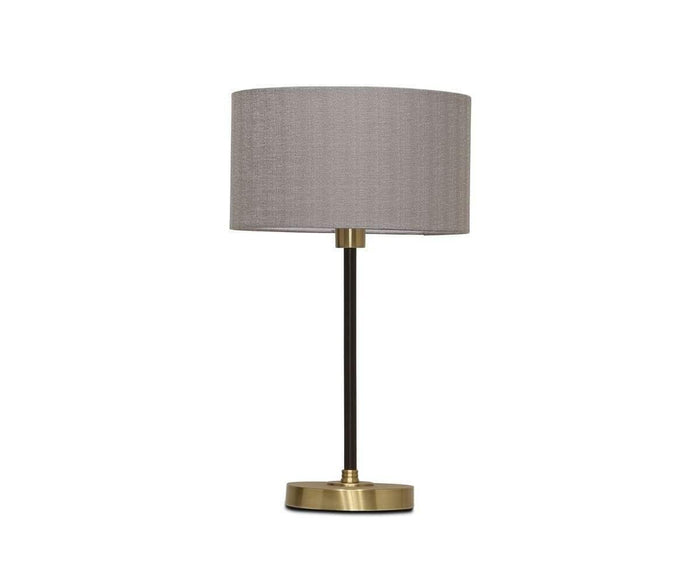 The Doren Table Lamp is a modern lamp featuring a brass finish, a cylindrical gray fabric shade, a slender black stand, and a round base, set against a white background.