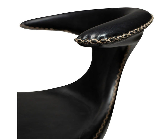 Close-up of the Drake Counter Stool featuring black faux leather upholstery, a curved armrest, and visible tan stitching along the edges, highlighting its craftsmanship and distinctive modern Danish design.