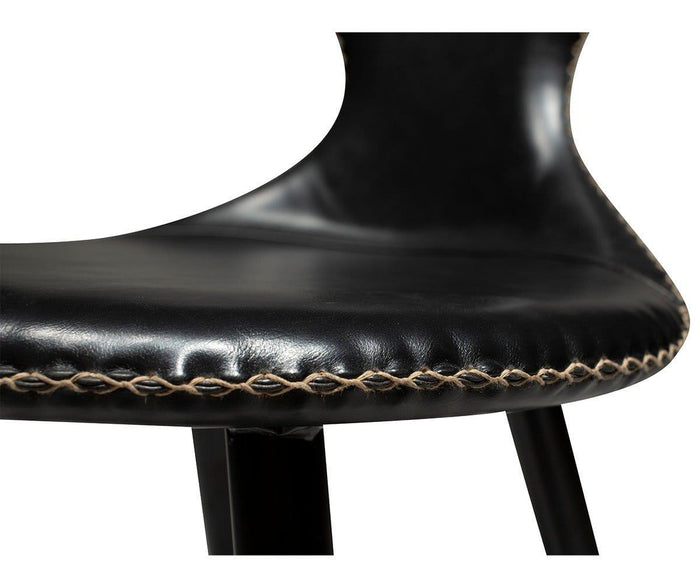Close-up of the Drake Counter Stool’s modern black faux leather seat with light-colored stitching detail along the edge and part of the curved backrest visible, reflecting modern Danish design.
