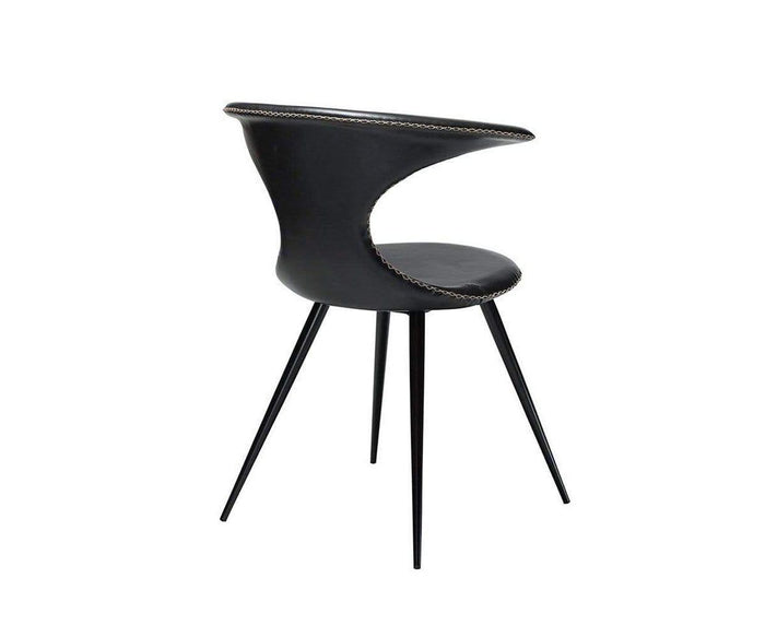 The Drake Dining Chair is a modern black faux leather chair with a curved backrest, open design, and slender metal legs. The seat and back are cushioned for comfort, while the backrest is accented with decorative stitching along the edge. This contemporary Danish-inspired chair is photographed on a white background.