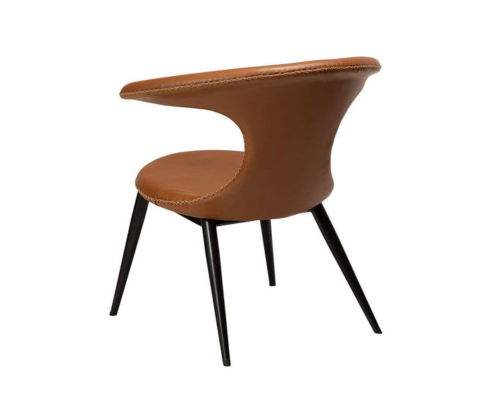 The Drake Lounge Chair is a modern brown accent chair featuring a curved backrest, open sides, and visible stitching. Supported by four slender black legs, this chair combines rustic industrial elements with contemporary style. Crafted from high-quality faux leather, the Drake Lounge Chair is displayed against a plain white background.