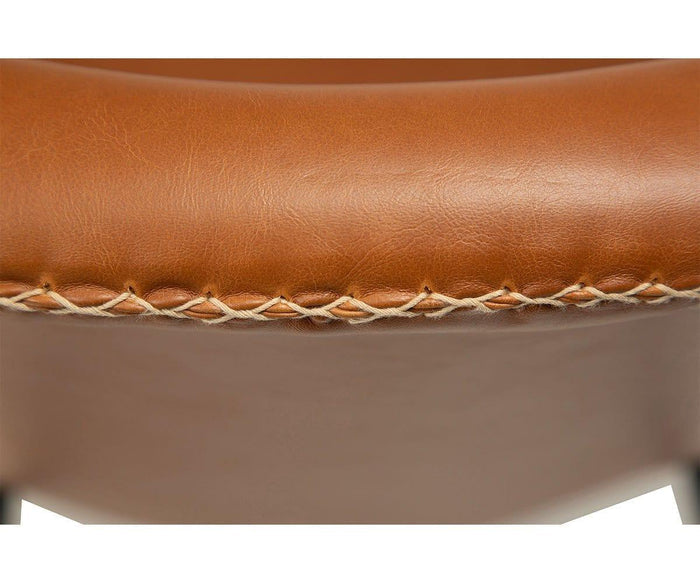 Close-up of the Drake Lounge Chair’s brown faux leather upholstery with visible white stitching along the edge, highlighting its textured surface and craftsmanship—a refined detail that showcases its rustic industrial design.