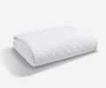 A white Dri-Tec Mattress Protector, featuring a quilted hexagonal pattern and folded neatly on a plain light background, highlights its breathable design inspired by advanced Performance Mattress Protector technology.