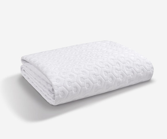 A white Dri-Tec Mattress Protector, featuring a quilted hexagonal pattern and folded neatly on a plain light background, highlights its breathable design inspired by advanced Performance Mattress Protector technology.