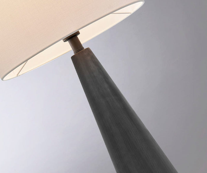 Close-up of the Dyre Table Lamp, a modern cordless outdoor table lamp featuring a white fabric shade and a dark, cone-shaped black cement base, set against a light gray background.