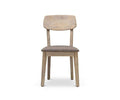 The Eckler Dining Chair, shown facing forward on a white background, features a solid acacia wood frame in a Havana Grey finish, with a rectangular backrest and a padded brown upholstered seat.