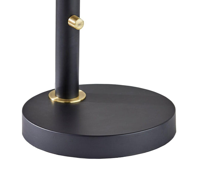 Close-up of the Eden Task Lamp’s black circular base, featuring a vertical pole and a small brass knob near the bottom, showcasing its sleek design.