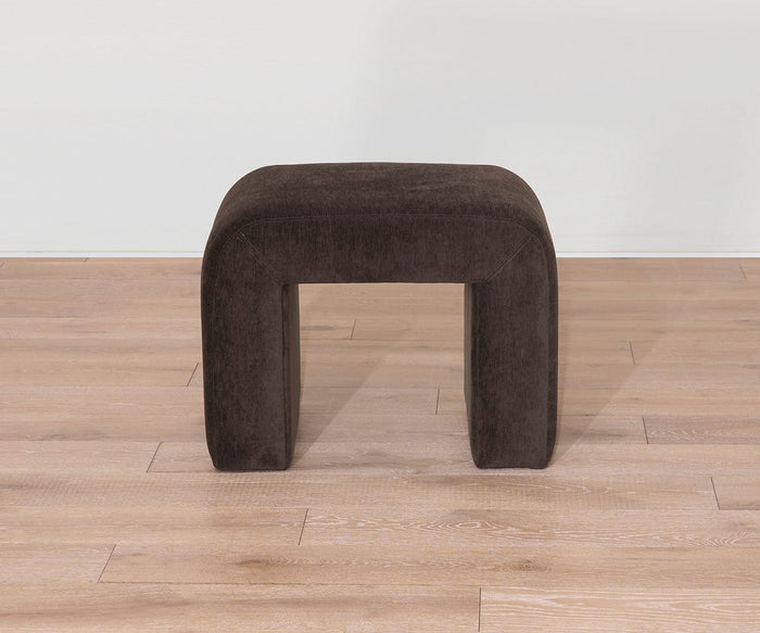 The Eilir Half Bench, featuring a dark brown rectangular design with rounded edges, sits on a light wood floor against a plain white wall, providing extra seating and infusing the space with contemporary flair.