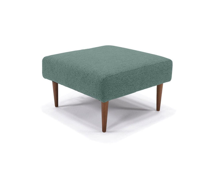 The Ella Ottoman features a square design in teal with textured fabric upholstery and four angled wooden legs, displayed on a white background—making it the perfect accent piece for any mid-century modern space.