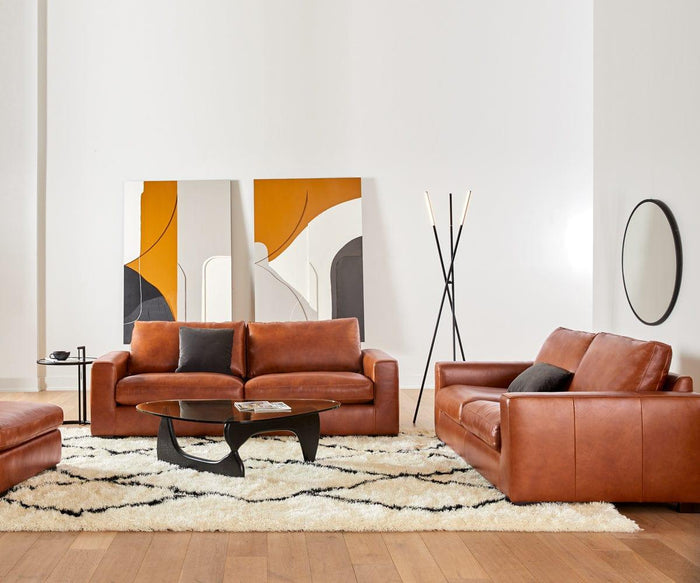 Modern living room with brown leather sofas, a black coffee table, a white rug with black lines, minimalist art against the wall, a round mirror, and wooden flooring. The space is elegantly illuminated by the Erick Floor Lamp and subtle rotating LED lights that add a dynamic ambiance to the decor.