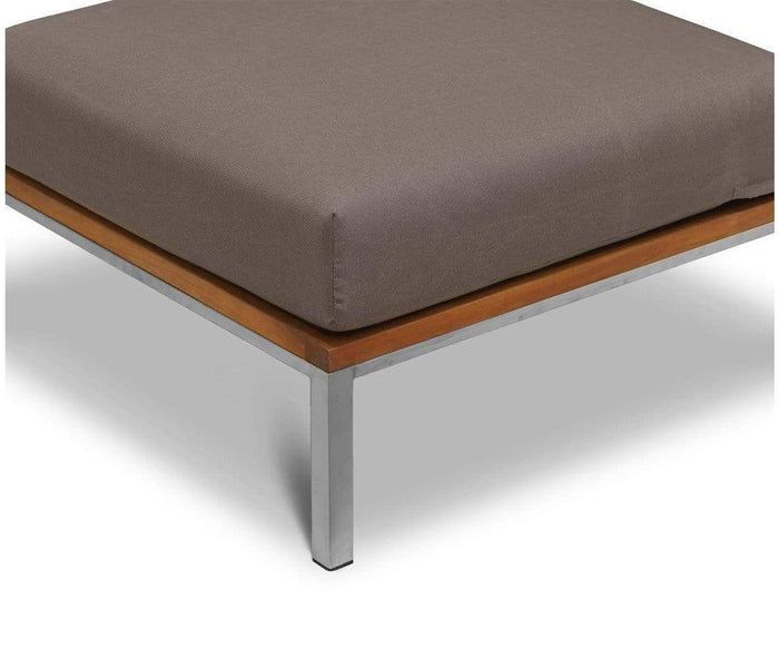 A close-up of the corner of the Farino Outdoor Ottoman featuring a thick, UV-resistant brown cushion, wooden trim, and sleek metal legs on a white background.