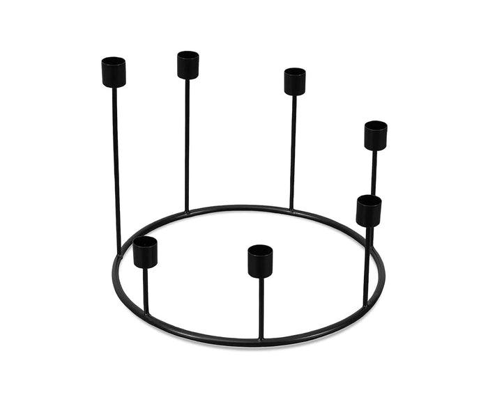 The Fina Candle Wreath is a minimalist black metal candle holder featuring a circular base with six evenly spaced upright holders, handcrafted in India for a striking decorative accent.