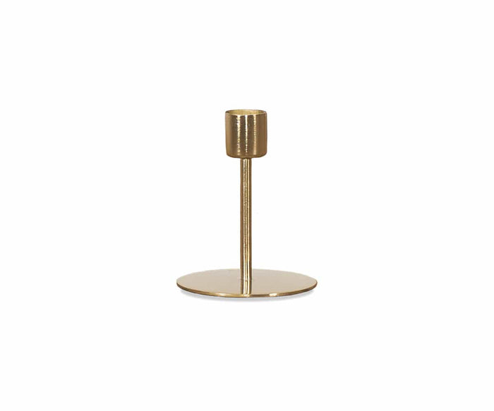 The Fina Candlestick, handcrafted from gold metal, features a round flat base and a single vertical stem designed to hold one candle, displayed against a plain white background.