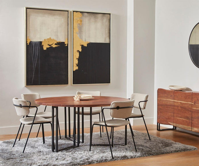 A round wooden dining table with four Finn Dining Chairs in beige sits on a gray rug. Abstract gold and black art hangs on the wall, with a wooden sideboard and round mirror in the background.
