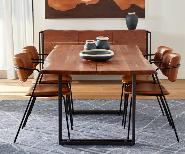 Six Finn Dining Chairs in brown leather surround a rectangular wooden dining table with black metal legs. The table is decorated with three ceramic vases, and a wooden sideboard along with abstract art can be seen in the background.