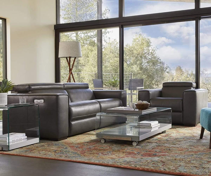 Modern living room featuring a black leather sofa and armchair, glass coffee and side tables, the Gaffel Floor Lamp with its elegant tripod base, expansive windows, and views of sunlit trees outside—creating a perfect fusion of elegance and contemporary home decor.