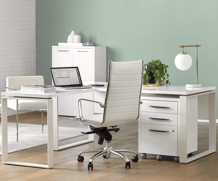 Modern office with a white desk, swivel chair, laptop, documents, lamp, potted plant, and the Gammel Low Bookcase with Doors in white for added storage against a green wall. Wooden floor and minimalist decor create a clean, contemporary workspace.