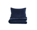 A neatly folded Geometric Velvet Quilt + Sham Set in navy, crafted from plush velvet with a matching sham, stands against a plain white background.