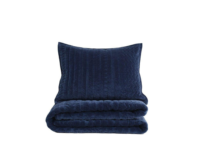 A neatly folded Geometric Velvet Quilt + Sham Set in navy, crafted from plush velvet with a matching sham, stands against a plain white background.