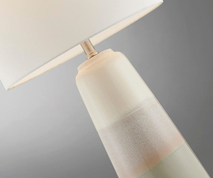 Close-up of the Ghazi Table Lamp, featuring a white linen shade and a ceramic base in soft cream and beige tones, set against a neutral background.