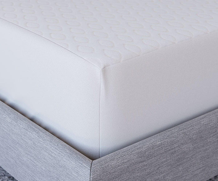 Close-up of a mattress corner with a white textured cover, neatly fitted on a light gray upholstered bed frame, showcasing the Hälsa Sleep™ Ultra Mattress Protector for added comfort and protection.