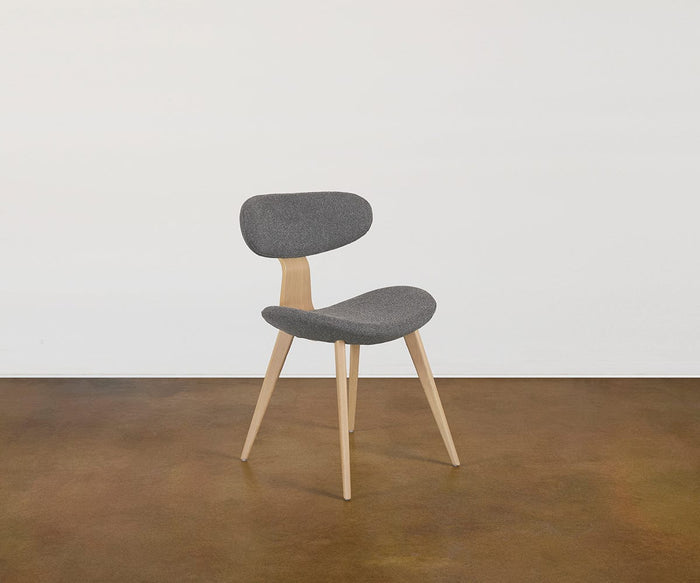 The Hana Dining Chair in Grey/Oak, featuring solid white oak legs and a gray performance fabric upholstered seat and backrest, sits on a brown floor against a plain white wall.