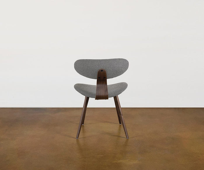 The Hana Dining Chair, featuring a gray performance fabric seat and backrest paired with solid white oak legs and support, is centered on a brown floor against a plain white wall.