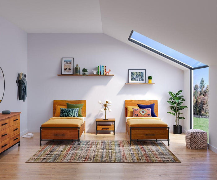 Two single beds with colorful pillows, a nightstand, dresser, and indoor plant in a modern bedroom with a skylight and wall shelves—including the striking Hasse 71″ Shelf that adds character to the space—all set atop a patterned rug over wooden flooring.