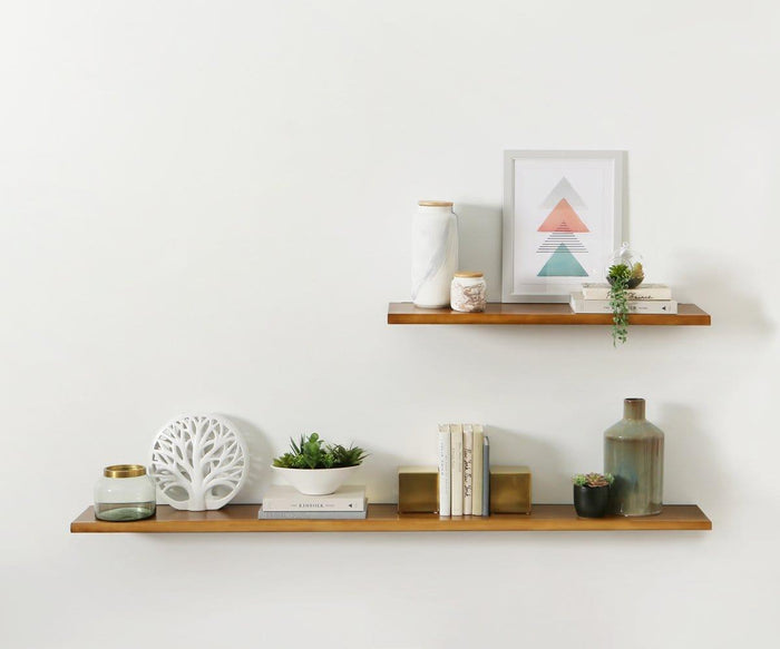 Two Hasse 71″ shelves, including a rustic wood design, display books, small plants, a white tree decor, candles, a framed geometric print, and decorative vases against a plain white wall.