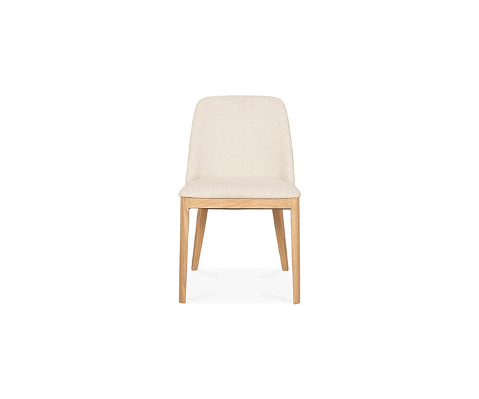 A front-facing view of the Hendrick Dining Chair - White Oak, showcasing its white oak frame with light wood legs and a beige cushioned seat and backrest, isolated on a white background.