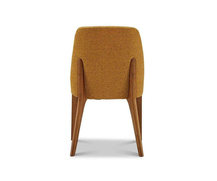 The Hendrick Dining Chair, a mid-century modern design with mustard yellow upholstery and wooden legs, features a cushioned seat and is shown from the back against a white background.